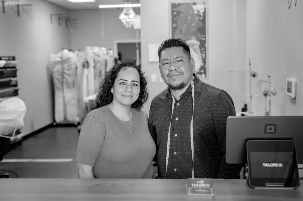 Expert Tailors Edin and Martha standing proudly inside the shop