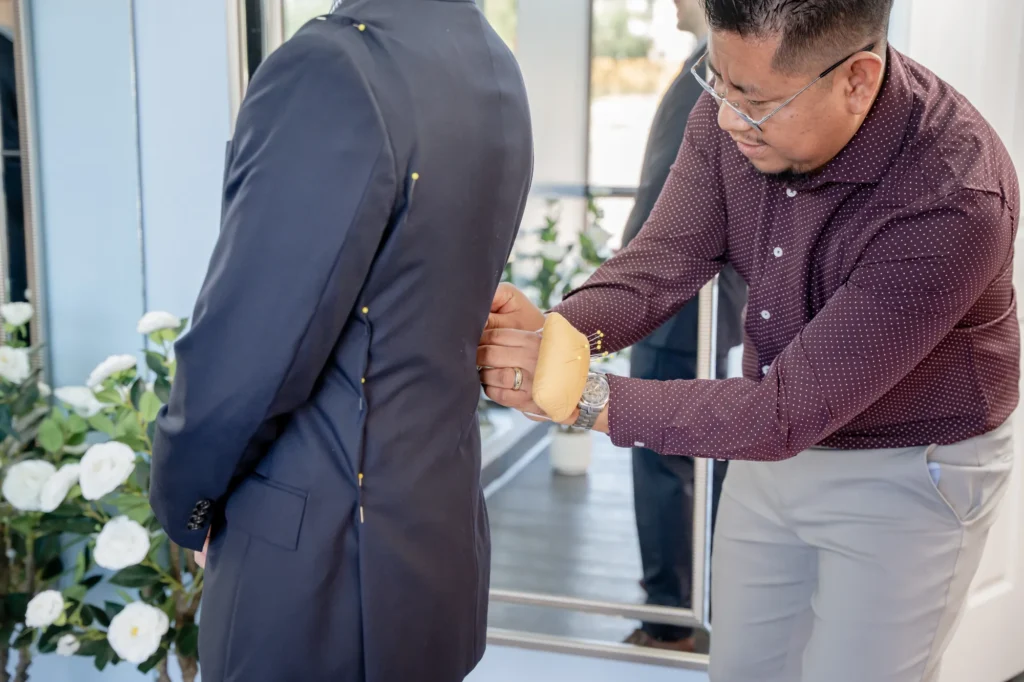 Expert tailor pinning to reduce the shoulders and sides of a suit jacket coat