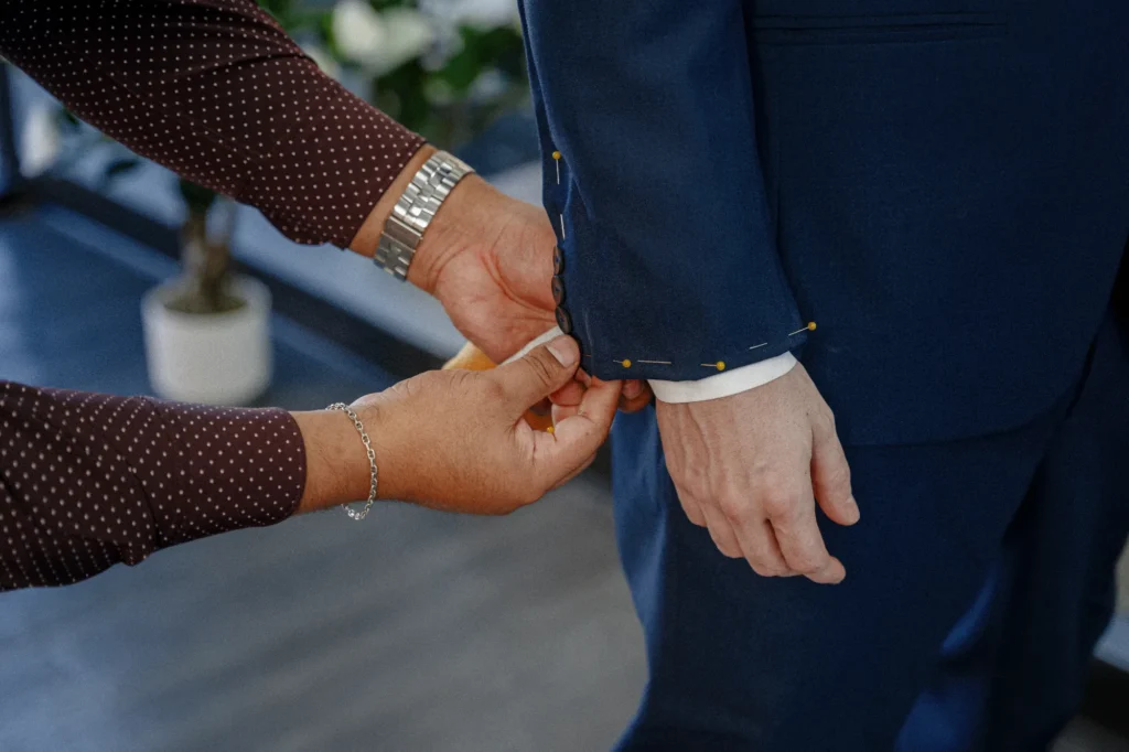 Professional tailor pinning and adjusting suit sleeve length