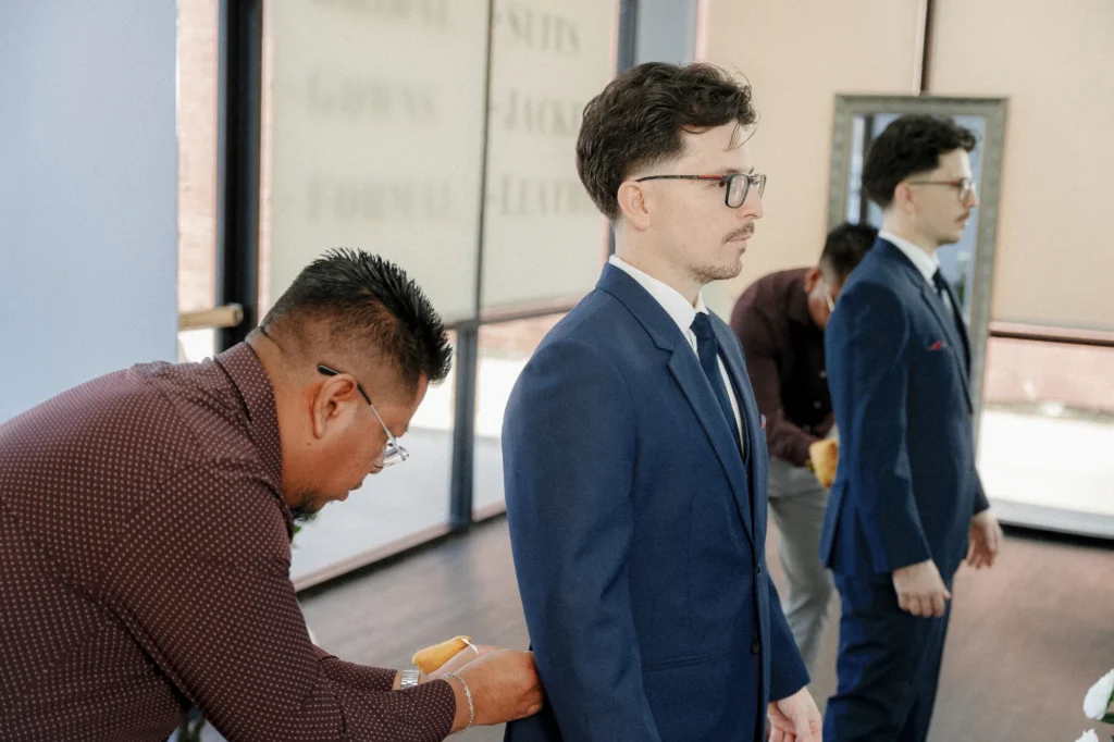 Professional tailor pinning the sides in suit jacket on a client